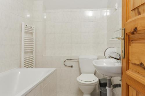 a white bathroom with a toilet and a sink at Penzion Koliba in Tatranská Kotlina