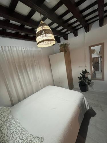 a bedroom with a white bed and a chandelier at Apartamento Jerez Centro San Miguel in Jerez de la Frontera