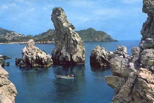 a boat in the water next to some rocks at Holiday Home Gionny & Mary in Taormina