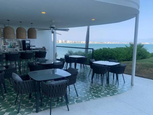a restaurant with tables and chairs with a view of the ocean at Nuevo y Moderno Depto en Tizate in Nuevo Vallarta