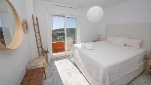 a white bedroom with a bed and a window at Bellavista 5E in Manilva