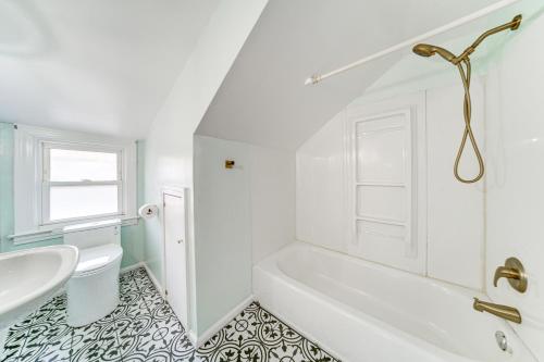 Baño blanco con bañera y lavamanos en Coastal Lake Erie Cottage with Amazing Water Views! en Euclid