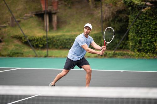 a man holding a tennis racket on a tennis court at Ort Hotel in Campos do Jordão