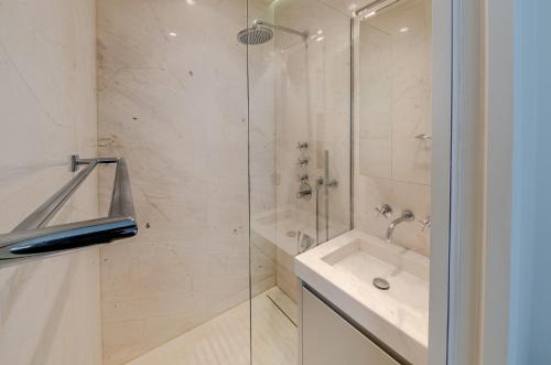 La salle de bains est pourvue d'une douche en verre et d'un lavabo. dans l'établissement TUILERIES - VENDOME, à Paris