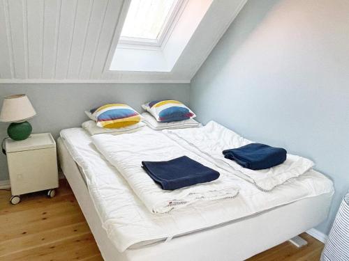 un letto con lenzuola e cuscini bianchi in una stanza di Holiday home SÖLVESBORG V a Sölvesborg