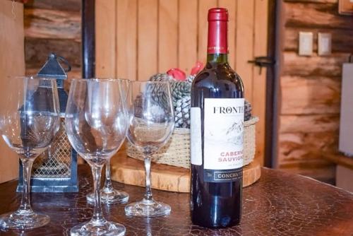 a bottle of wine sitting on a table with wine glasses at Finca Chuchiyá cabañas Tecpan in Tecpán Guatemala