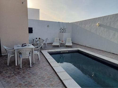 een patio met een tafel en stoelen en een zwembad bij Villa phare 1 Midoun in Midoun