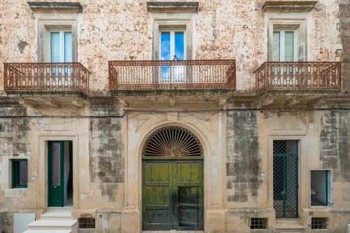 stary budynek z zielonymi drzwiami i balkonem w obiekcie Palazzo Rizzo w mieście Spongano