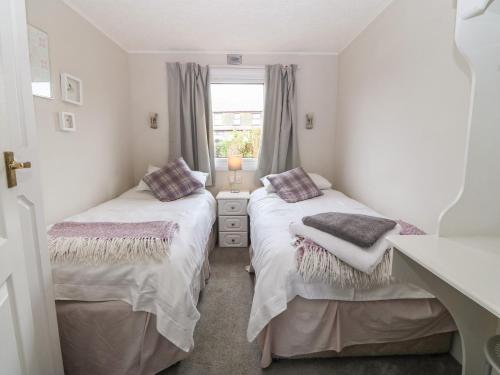 two beds in a small room with a window at Caban Tywod in Pwllheli