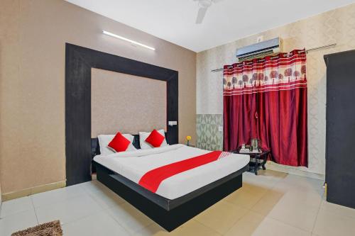una camera da letto con un grande letto con tende rosse di OYO Hotel Sargam a Ahmedabad