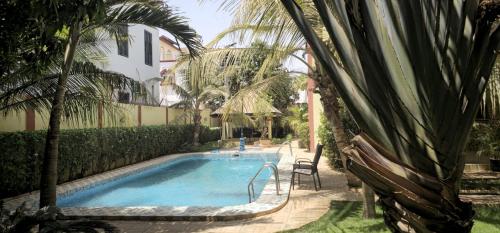 a swimming pool with a palm tree next to a house at Villa L'Oasis in Ouagadougou