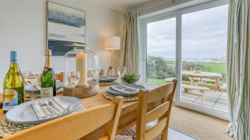 a dining room with a table with wine bottles at Penrhyn Isa Un in Aberffraw