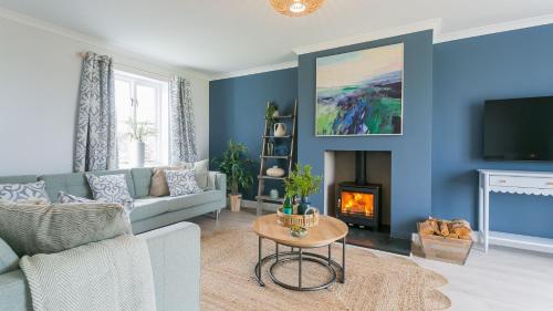 a living room with a couch and a fireplace at Penrhyn Isa Un in Aberffraw