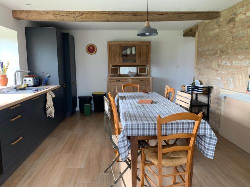 une cuisine et une salle à manger avec une table et des chaises dans l'établissement Jolie maison de campagne au cœur du Brionnais, à Saint-Laurent-en-Brionnais