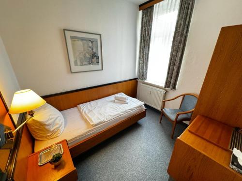 a bedroom with a bed and a chair and a window at Hotel zur Eiche in Meerane