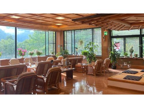 un restaurante con sillas, mesas y ventanas en Nakanoyu Onsen Ryokan - Vacation STAY 07493v, en Matsumoto