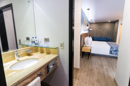 a bathroom with a sink and a bed at GHL Hotel Abadia Plaza in Pereira