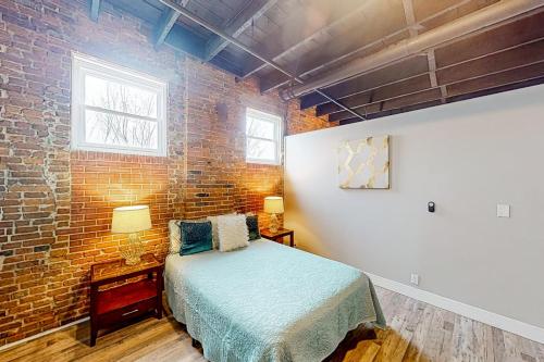 a bedroom with a bed and a brick wall at Broadway Loft in Saint Louis