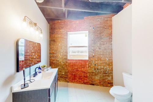 a brick wall in a bathroom with a sink and a mirror at Broadway Loft in Saint Louis