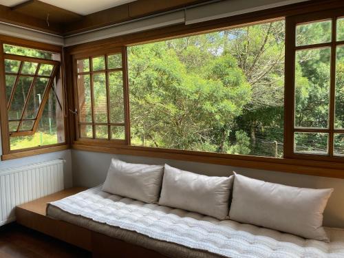 a couch in a room with two windows at Apartamento Quinta da Serra - Canela in Canela