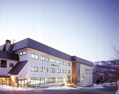 a large building with snow on the ground at Shiga Kogen Olympic Hotel in Yamanouchi