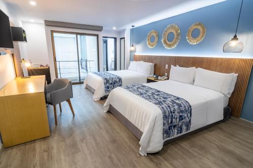 a hotel room with two beds and a desk at GHL Hotel Abadia Plaza in Pereira