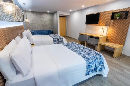 a hotel room with two beds and a desk at GHL Hotel Abadia Plaza in Pereira