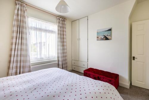 1 dormitorio con 1 cama blanca y 1 silla roja en Victoria Cottage-seconds to beach-pet friendly- easy parking- self check in-sleep 6 people-minutes walk to all amenities en Deal