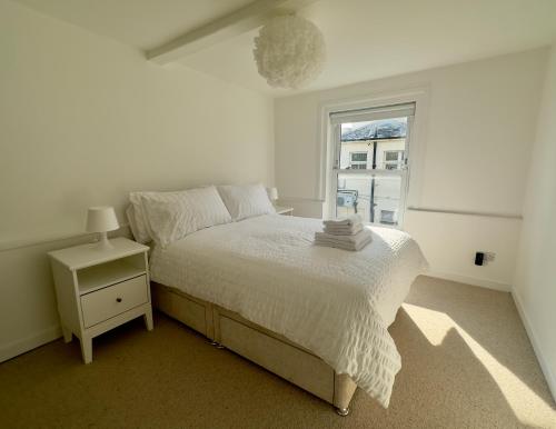 ein weißes Schlafzimmer mit einem Bett und einem Fenster in der Unterkunft Buttercup Cottage Off-Street Parking 2 Large SUVs 3 Minutes to Beach in St. Leonards