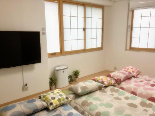 two beds in a room with a flat screen tv at 2nd and 3rd floor - Vacation STAY 16315 in Osaka
