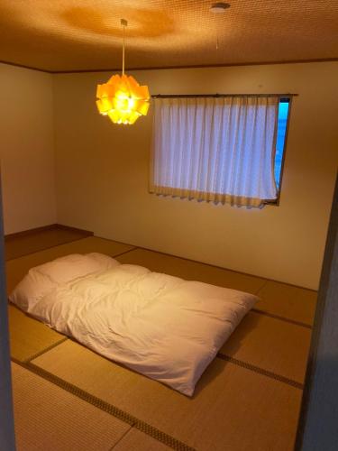 Bett in einem Zimmer mit einem Fenster und einem Kronleuchter in der Unterkunft Minshuku Miyoshi - Vacation STAY 14454v in Echizen
