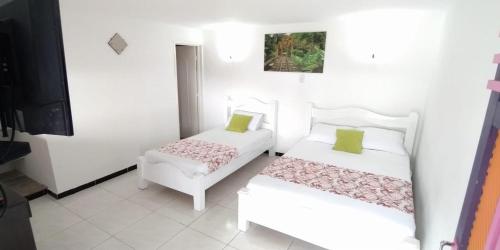 a bedroom with two beds and a tv at HOTEL CAMPESTRE EL CORTIJO in Santa Rosa de Cabal