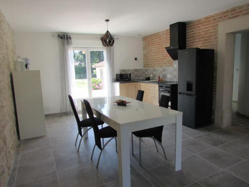 uma cozinha com uma mesa branca e electrodomésticos pretos em L'Étape Bourguignonne (proche Beaune et Chalon) em Sermesse