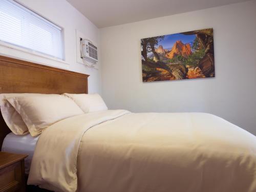 a bedroom with a white bed with a picture on the wall at RAD Hostel in Colorado Springs