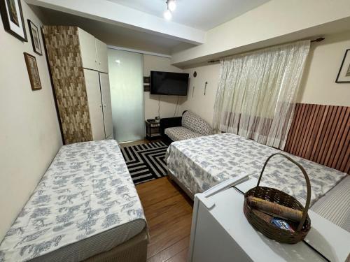 Habitación pequeña con 2 camas y TV. en Hostel Tia Ana, en São Paulo