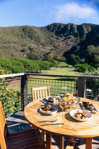 a wooden table with plates of food on a balcony at The Ranch at Laguna Beach in Laguna Beach