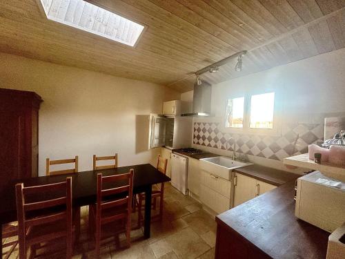 une cuisine avec une table, des chaises et un évier dans l'établissement Gite - maison de charme, à Saint-Vivien-de-Médoc