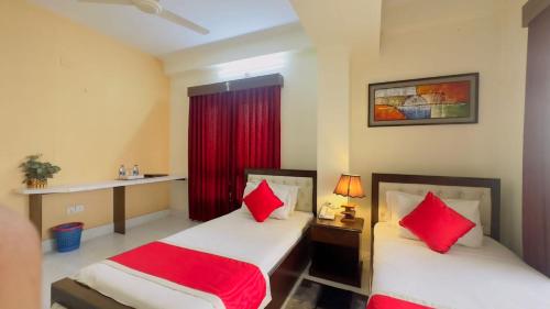 two beds in a hotel room with red pillows at Hotel Grand Circle Inn Dhaka in Dhaka