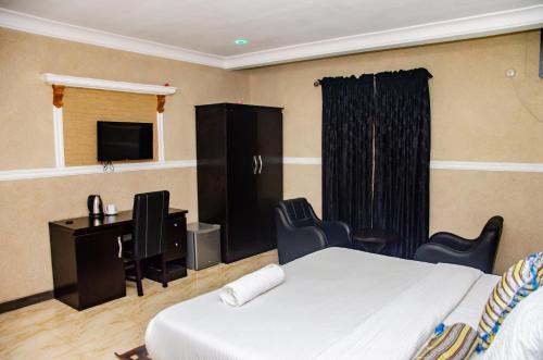 a bedroom with a bed and a desk and a television at Aify Queenest Hotel and Suites in Owerri