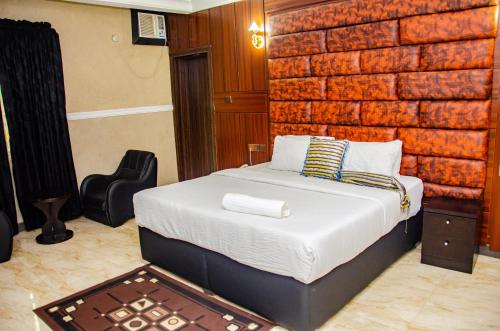 ein Schlafzimmer mit einem Bett und einer Ziegelwand in der Unterkunft Aify Queenest Hotel and Suites in Owerri