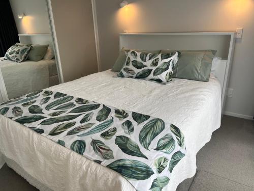 a bed with a green and white blanket and pillows at Rotorua Central Hosted B&B in Rotorua
