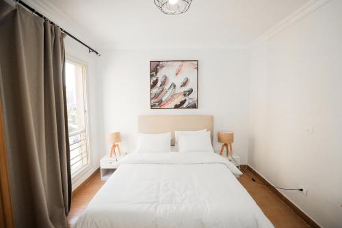 a white bedroom with a bed and a window at Cozy apartment New Cairo in New cairo
