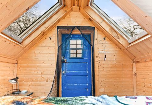 Una puerta azul en una habitación de madera con cama en Stargazer tiny house en Palenville