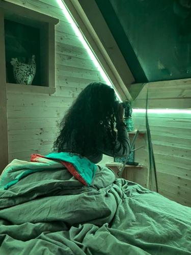 a person with long hair sitting on a bed at Stargazer tiny house in Palenville