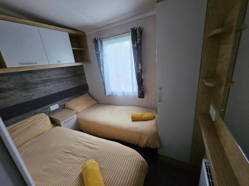 Cette petite chambre comprend 2 lits et une fenêtre. dans l'établissement Rockley Park, The Poplars, à Lytchett Minster