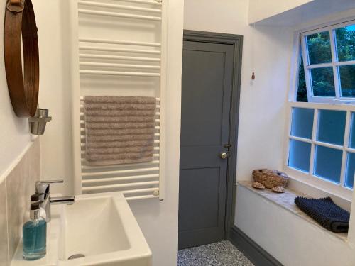 un bagno con lavandino, specchio e finestra di Cromwell Cottage a Fakenham
