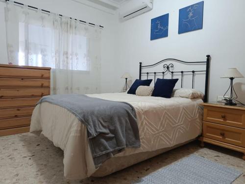 a bedroom with a bed with blue pillows and a dresser at Bonita casa en Sevilla in San Pablo