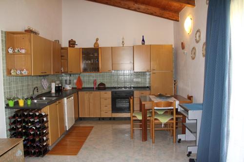 una cucina con armadi in legno, tavolo e sedie di Casa Vacanze Margherita a Riola Sardo