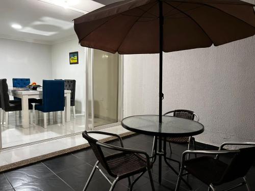 a table with chairs and an umbrella in a room at Casa frente al centro comercial Guatapuri in Valledupar