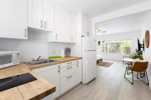 a kitchen with white cabinets and a white refrigerator at Victoria Park Unique Studio close to Las Olas Blvd in Fort Lauderdale
